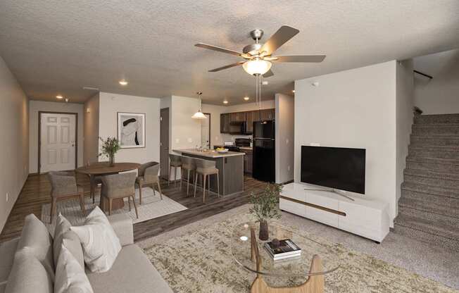A living room with a couch, a coffee table, a television, and a staircase.