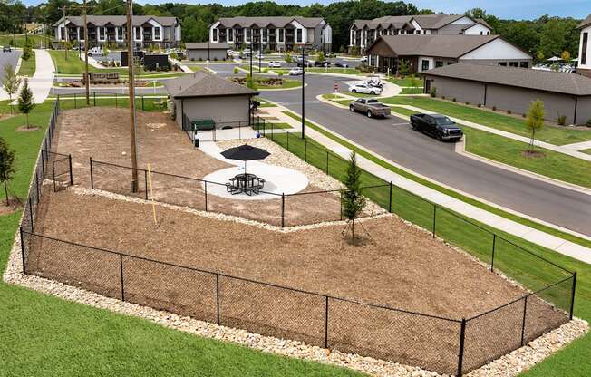 an aerial view of a fenced in park with a basketball court