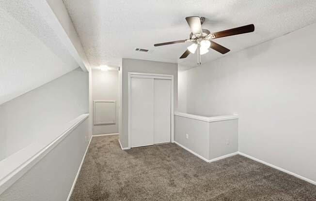 A room with a ceiling fan and carpeted floor.