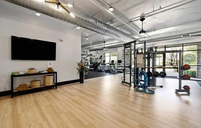 A gym with a variety of equipment including a treadmill, weights, and a television.