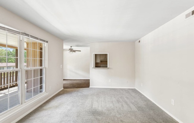 an empty living room with a window and a ceiling fan