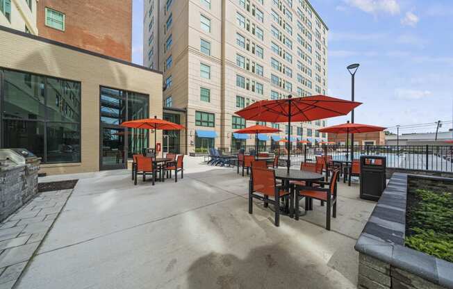 a patio with tables and umbrella  at The Icon, Richmond, VA, 23230s and a building in the background