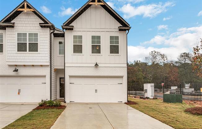 a white house with a garage door and a lawn