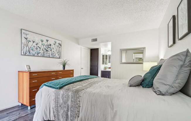 A bedroom with a bed, nightstand, and a plant.