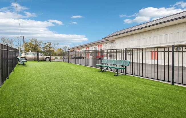 A green lawn in front of a building with a black fence.