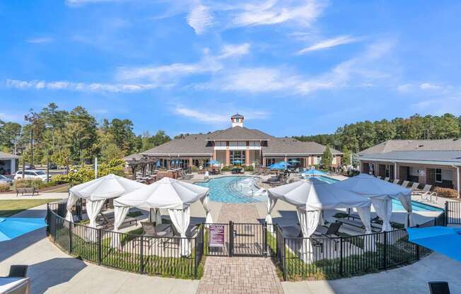A large swimming pool surrounded by white umbrellas and lounge chairs.