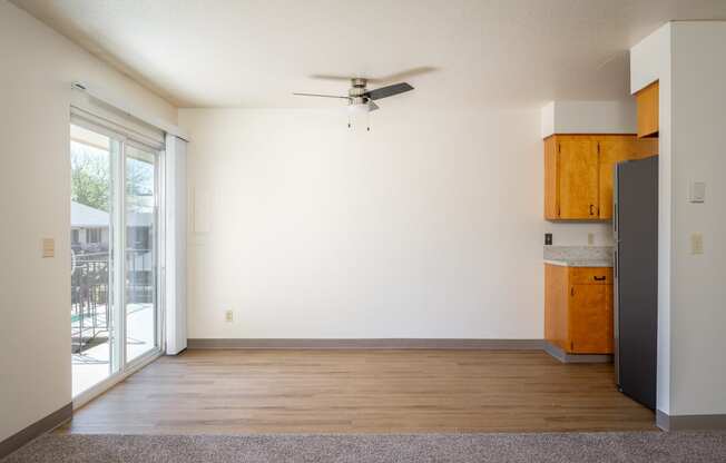 an empty living room with a ceiling fan and a window