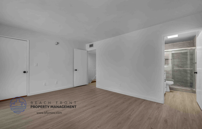 a bedroom with hardwood floors and white walls