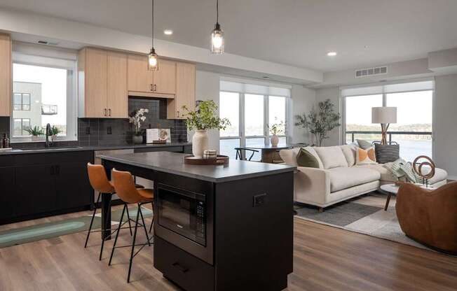 A modern kitchen with a black island and wooden floors.