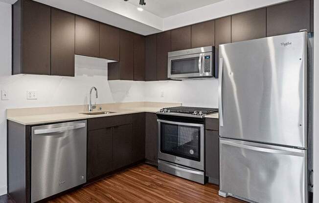 A modern kitchen with stainless steel appliances and wooden floors.
