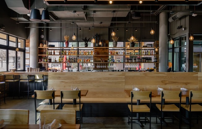 a restaurant with a bar and wooden tables and chairs at The Lucy Boise Apartments, Boise, ID