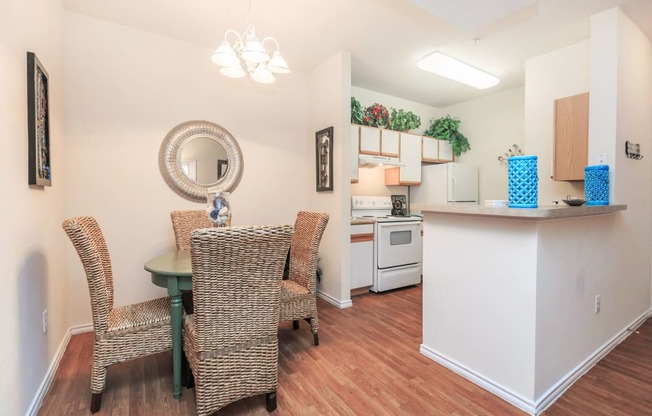 a dining room table with two chairs and a kitchen with a counter