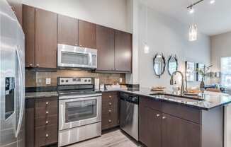 an apartment kitchen with stainless steel appliances and wooden cabinets
