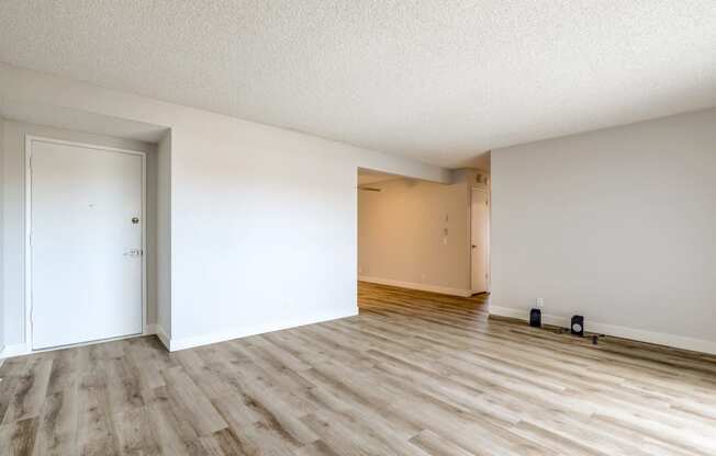 an empty living room with wood flooring and white walls