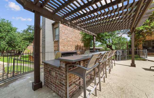A patio with a table and chairs under a pergola.