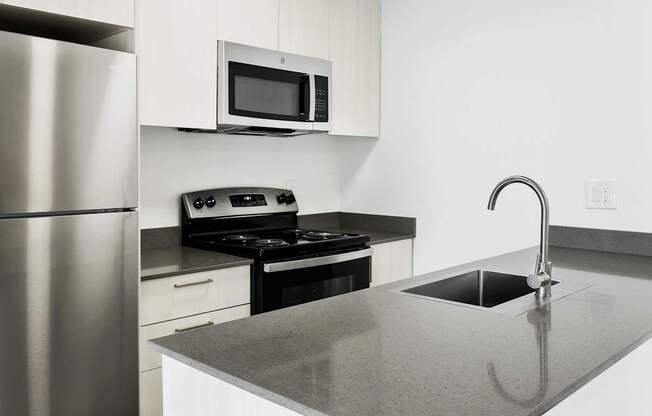 A modern kitchen with a stainless steel refrigerator, microwave, and oven.