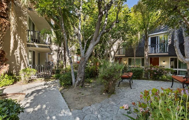 a courtyard with benches and trees in front of a building