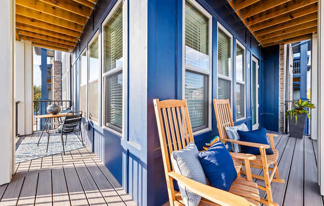 A balcony with wooden chairs and a table
