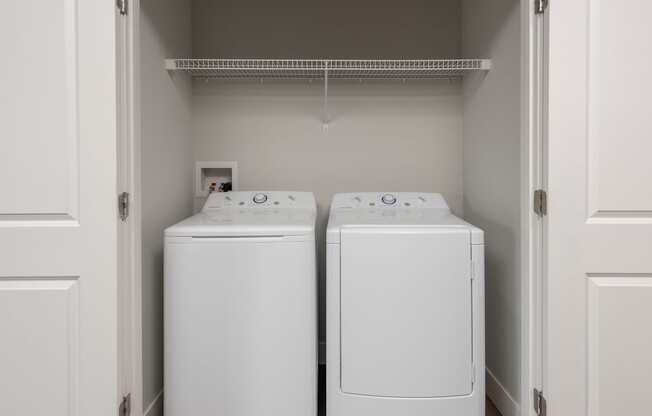 Two white front load washing machines in a laundry room.