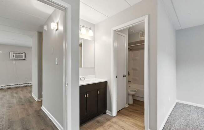 A bathroom with a toilet, sink, and mirror is visible through an open door.