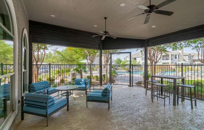 a covered patio with tables and chairs and a ceiling fan