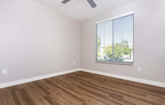 an empty room with wood floors and a window