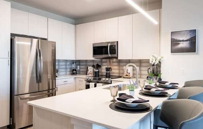 A modern kitchen with a white table set for a meal.