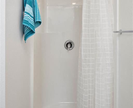 a bathroom with a white shower curtain and a blue towel