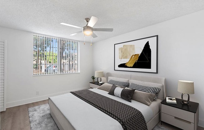 A bedroom with a large bed, a ceiling fan, and a painting on the wall.