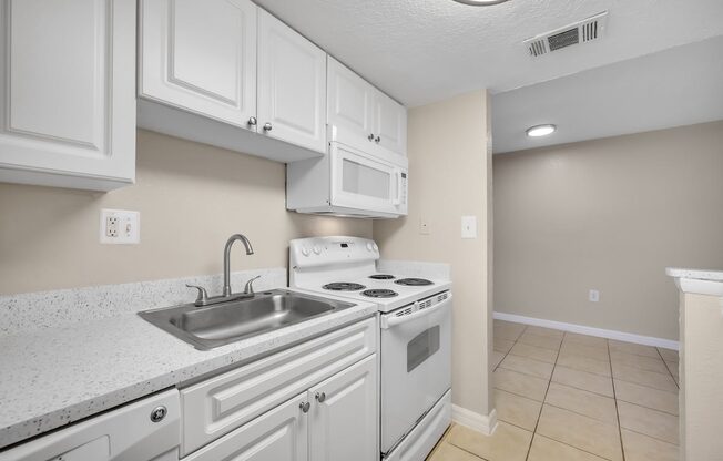 a kitchen with white appliances and white cabinets and a sink