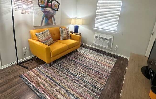 A living room with a yellow couch and a rug.