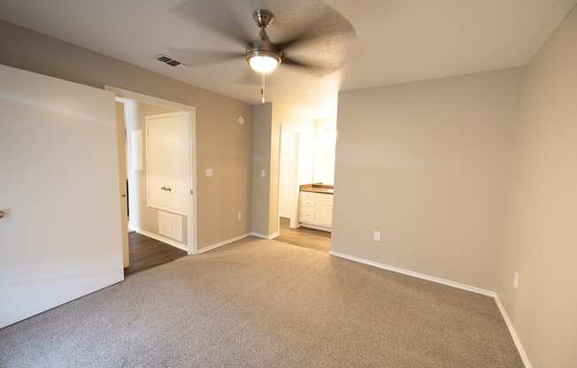 View of main bedroom looking into ensuite bathroom with carpet flooring, ceiling fan, and view in to hallway