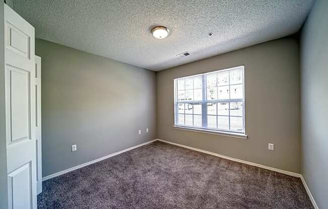 an empty room with carpet and a window