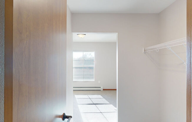a hallway with a wooden door and a tiled floor and a window