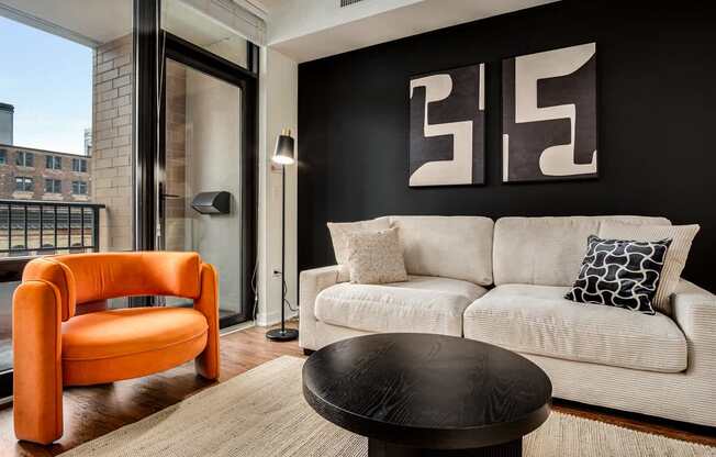 A living room with a white couch and an orange chair.