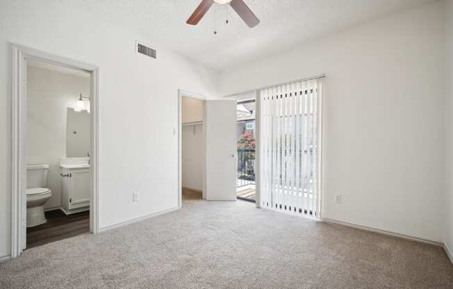 an empty living room with a sliding glass door to a bathroom