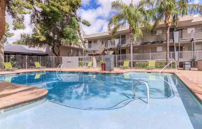 A swimming pool surrounded by palm trees and apartment buildings.