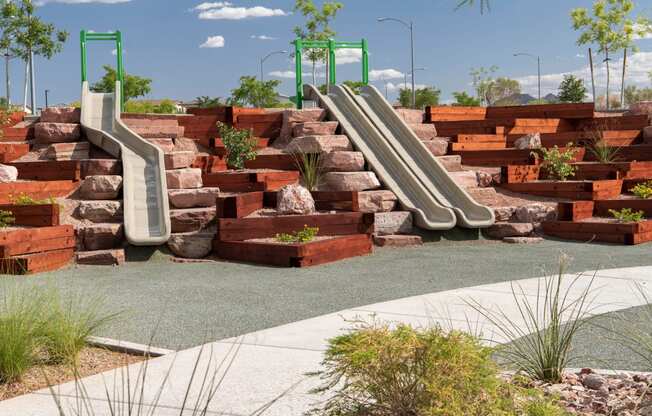 a playground with slides and rocks and plants