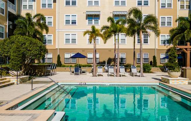 a swimming pool with palm trees in front of a building