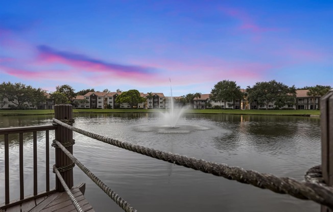 the fountain is in the middle of the pond at the preserve at sunset