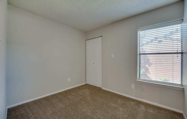 an empty bedroom with a large window and a door