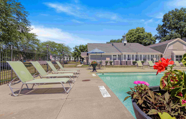 a pool with lounge chairs and a house in the background