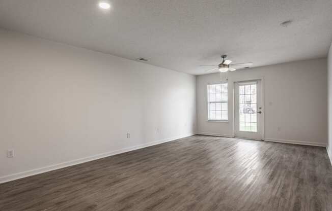 the living room of an empty house with white walls and a ceiling fan