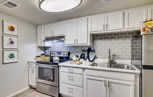 a kitchen with white cabinets and stainless steel appliances and a sink