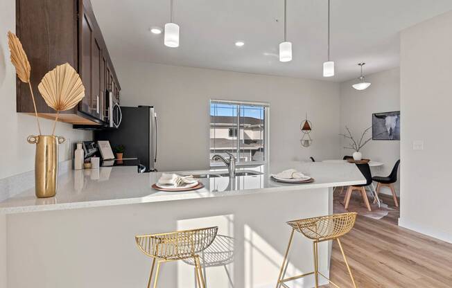 an open kitchen and dining area with a table and chairs at The Residences Apartments at Bear Tree | DeForest, WI, DeForest