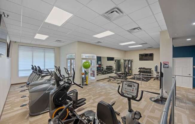 A gym with a variety of exercise equipment including treadmills, stationary bikes, and weight machines.