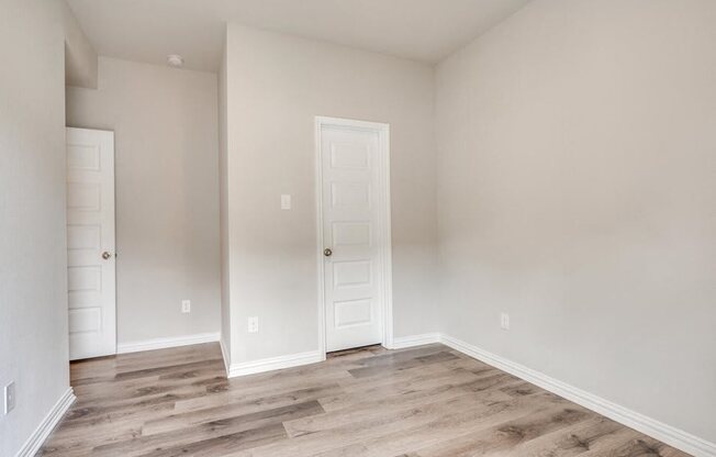 the living room of a home with a white door and wood flooring