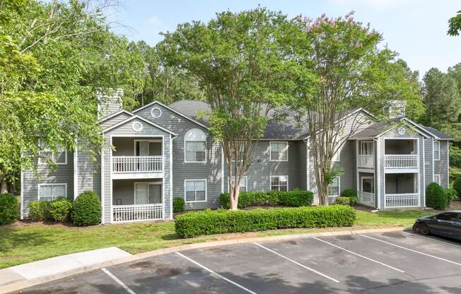 an apartment building with a parking lot and trees