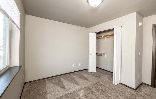 an empty room with a closet and a window