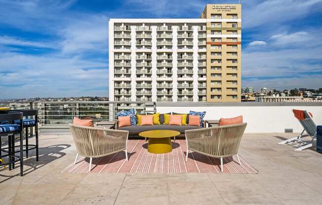 a rooftop patio with a couch and chairs and a building in the background